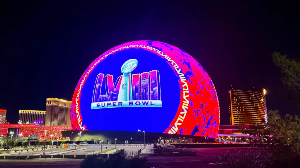 The Super Bowl LVIII logo displayed on the gigantic Las Vegas Sphere with skyscrapers in the surrounding background.